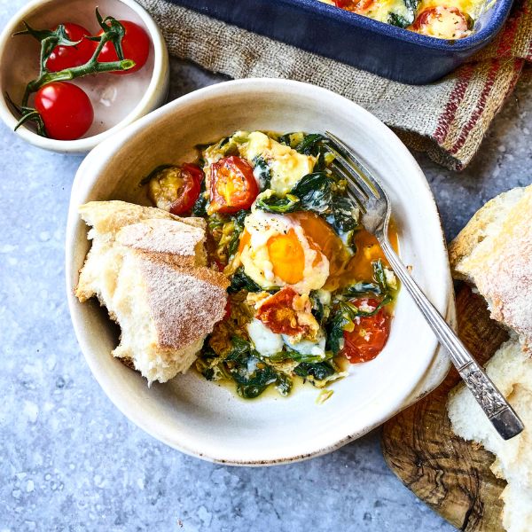 Cheesy baked eggs in bowl with pieces of bread